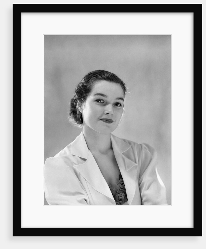 1930s portrait of young brunette woman looking at camera half smiling wearing white jacket with lapels by Anonymous