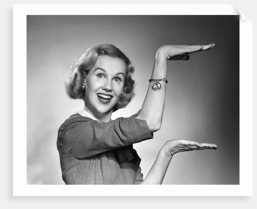 1950s 1960s happy smiling blond woman gesturing with hands showing size of something looking at camera by Anonymous