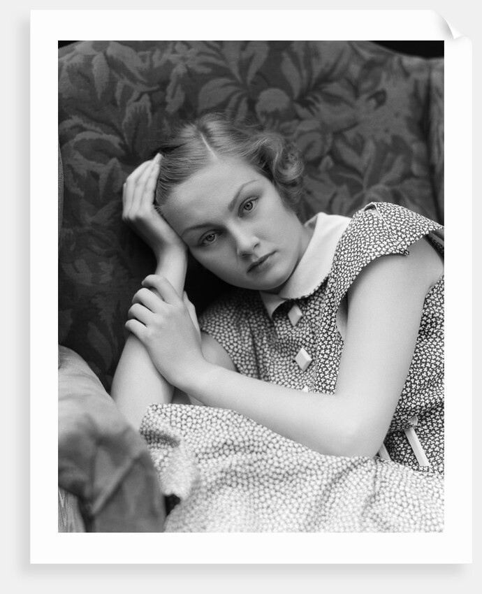 1930s woman moping looking sad or depressed or with a headache leaning her head on her hand looking at camera by Anonymous