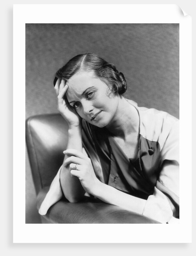 1930s 1940s woman sitting in chair worried sad expression one hand up to her forehead by Anonymous