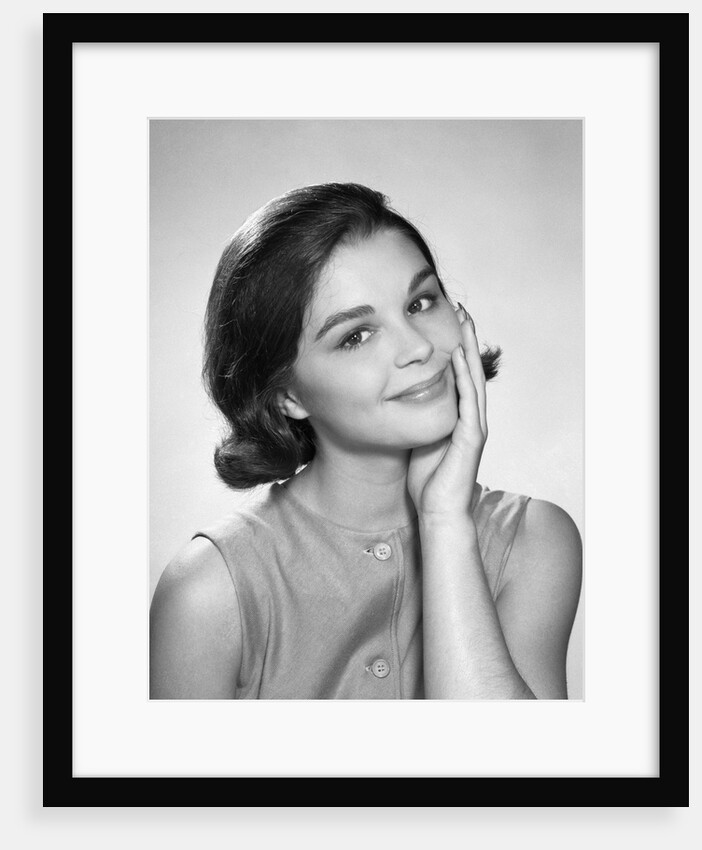 1960s smiling brunette young woman hand to cheek facial expression gesture looking at camera by Anonymous