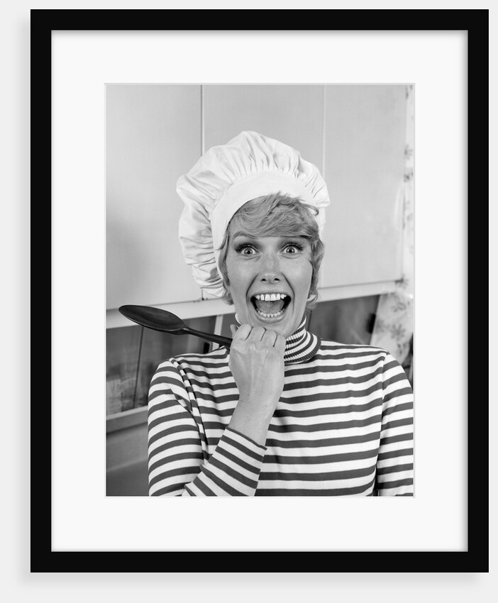 1970s woman portrait wearing chef's toque in kitchen with surprised face looking at camera by Anonymous