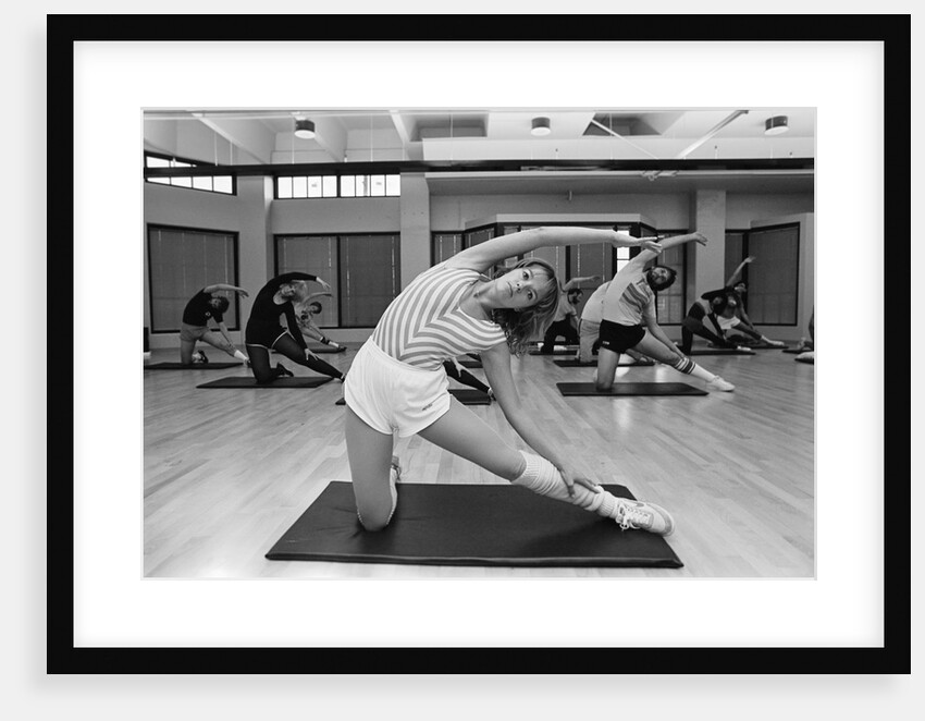 1980s aerobics class each person on an individual mat stretching looking at camera by Anonymous