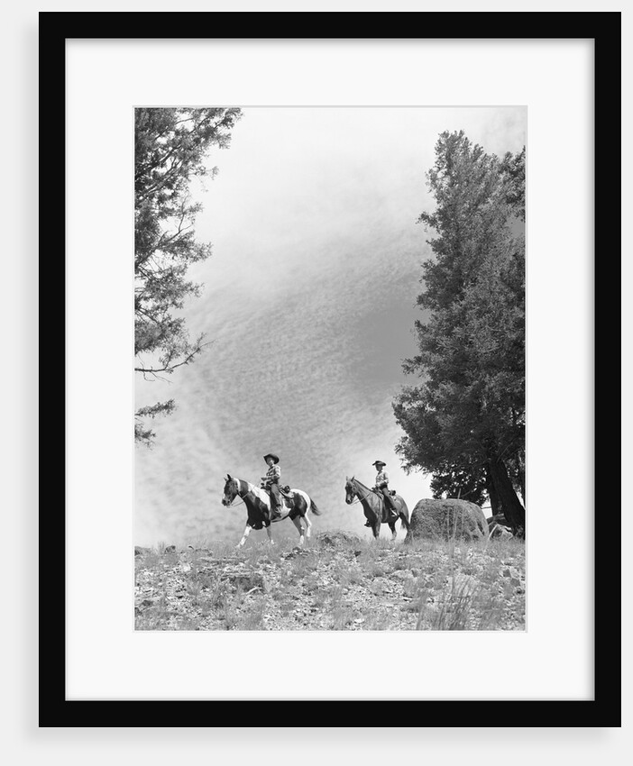 1950s 1960s two men on horseback riding across field wearing cowboy hats by Anonymous