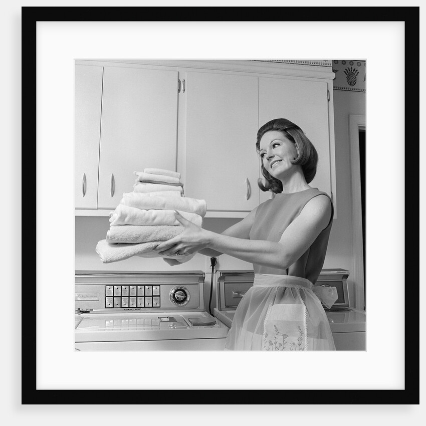 1960s satisfied woman homemaker holding folded laundry by Anonymous