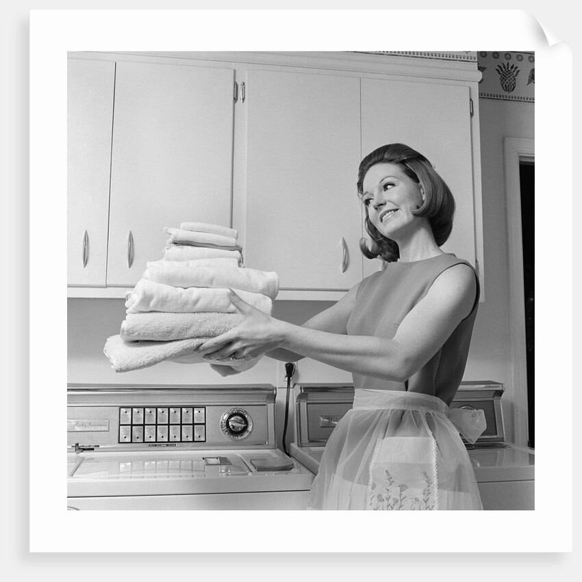 1960s satisfied woman homemaker holding folded laundry by Anonymous