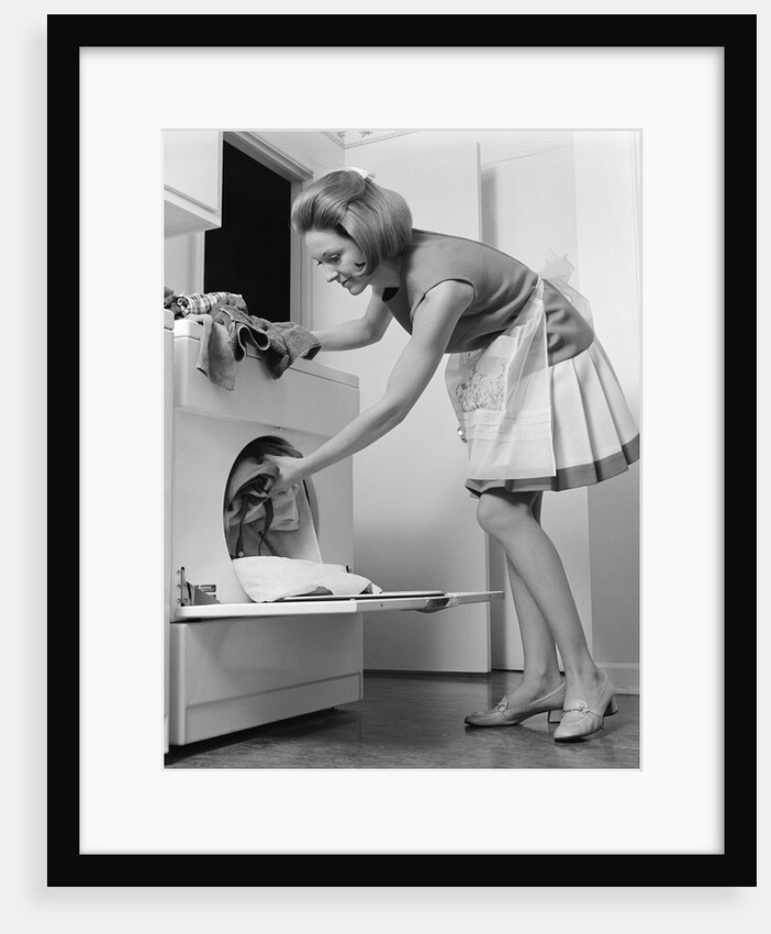 1970s woman removing laundry from dryer by Anonymous
