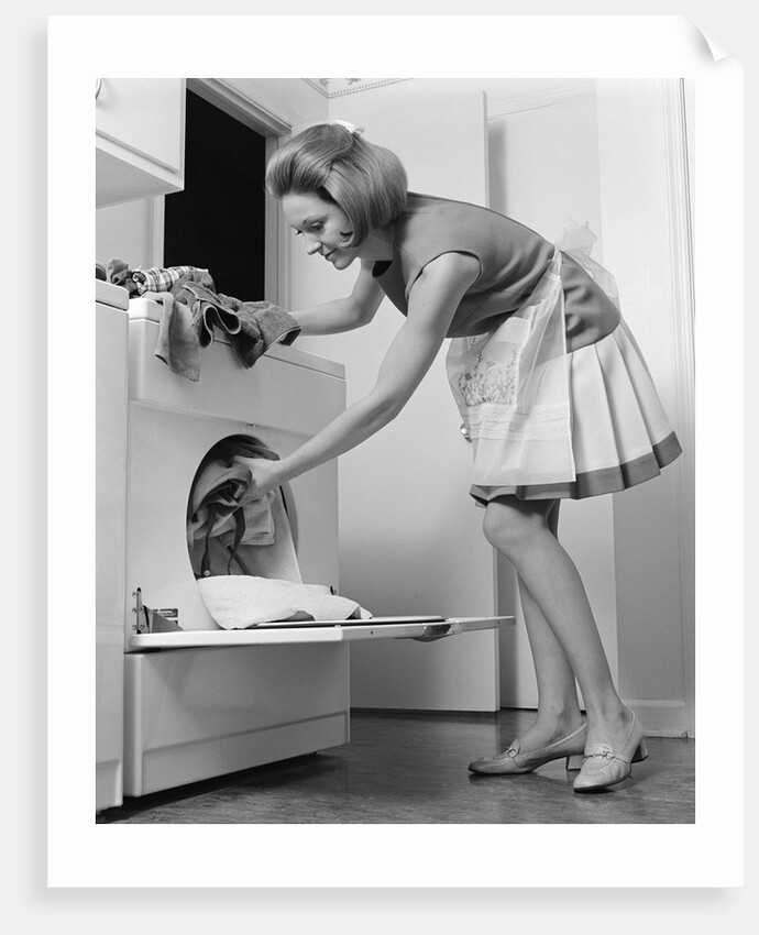 1970s woman removing laundry from dryer by Anonymous