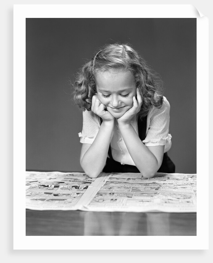 1940s child reading newspaper comics smiling by Anonymous