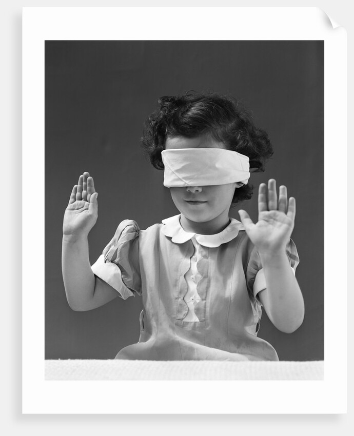 1940s child wearing blind fold with hands up in the air by Anonymous