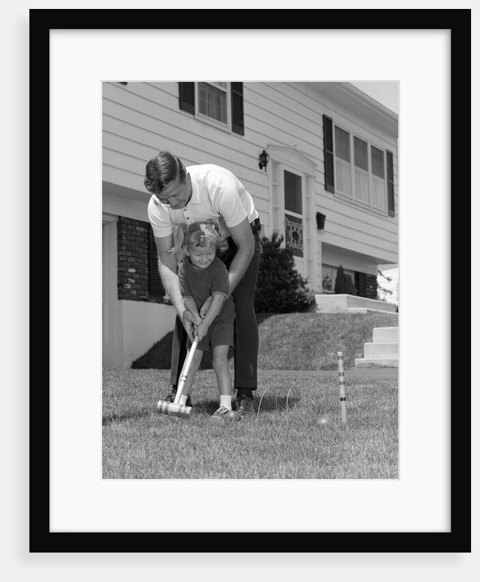 1960s father and young daughter playing croquet in yard by Anonymous