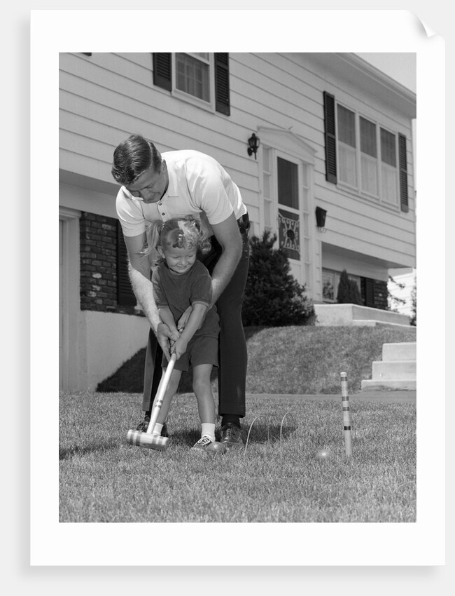 1960s father and young daughter playing croquet in yard by Anonymous