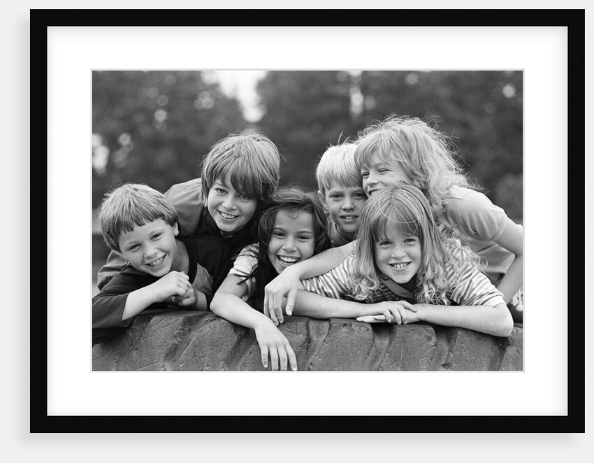 1970s 1980s group of six boys & girls gathered together on large playground tire by Anonymous