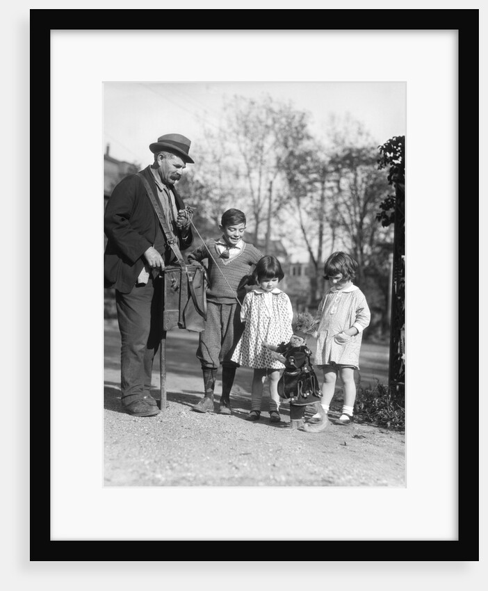 1920s group of three children watching organ grinder's monkey in costume standing on hind legs by Anonymous