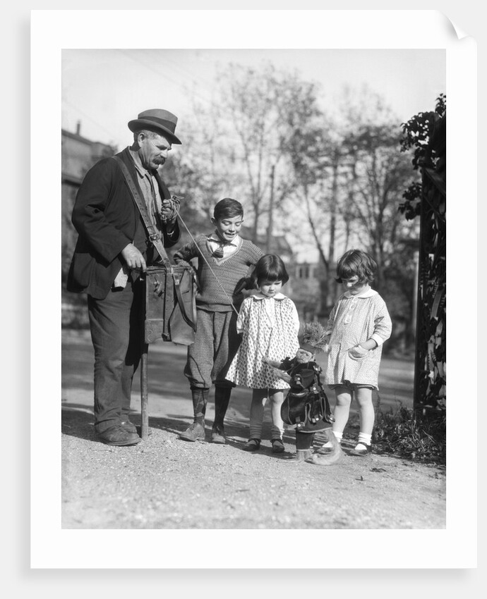 1920s group of three children watching organ grinder's monkey in costume standing on hind legs by Anonymous