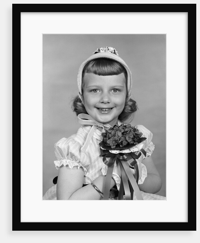 1950s child holding flowers smiling looking at camera by Anonymous