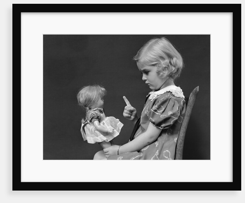 1930s little blond girl scolding her doll pointing finger by Anonymous