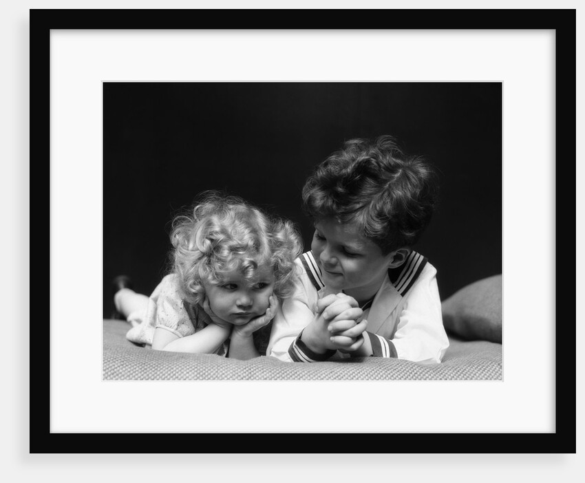 1930s two children brother and sister lying on couch by Anonymous