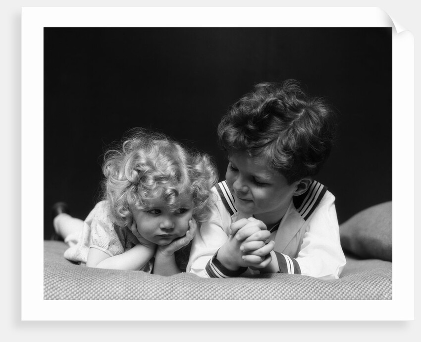 1930s two children brother and sister lying on couch by Anonymous