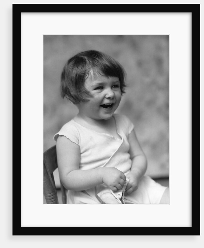 1930s smiling laughing toddler girl holding shoe by Anonymous