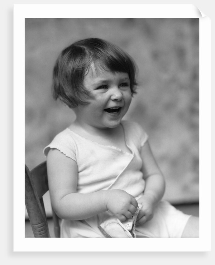 1930s smiling laughing toddler girl holding shoe by Anonymous