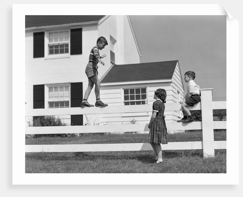 1950s boy walking balancing on fence other children standing sitting next to fence by Anonymous