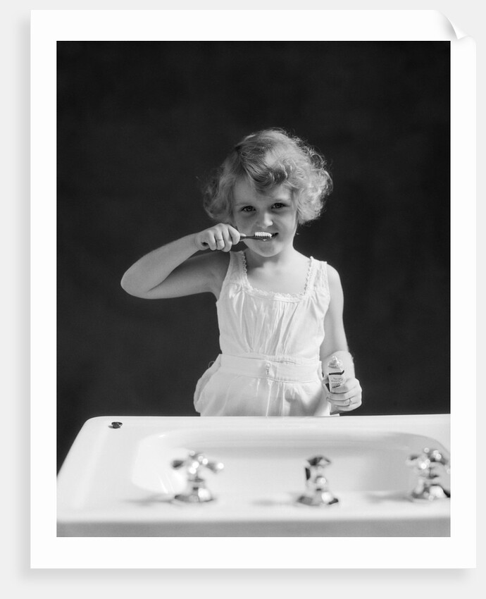 1930s child curly hair blond girl brushing teeth toothbrush looking at camera by Anonymous