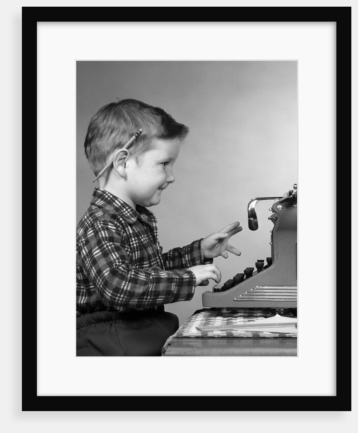 1950s smiling young boy typing on typewriter by Anonymous