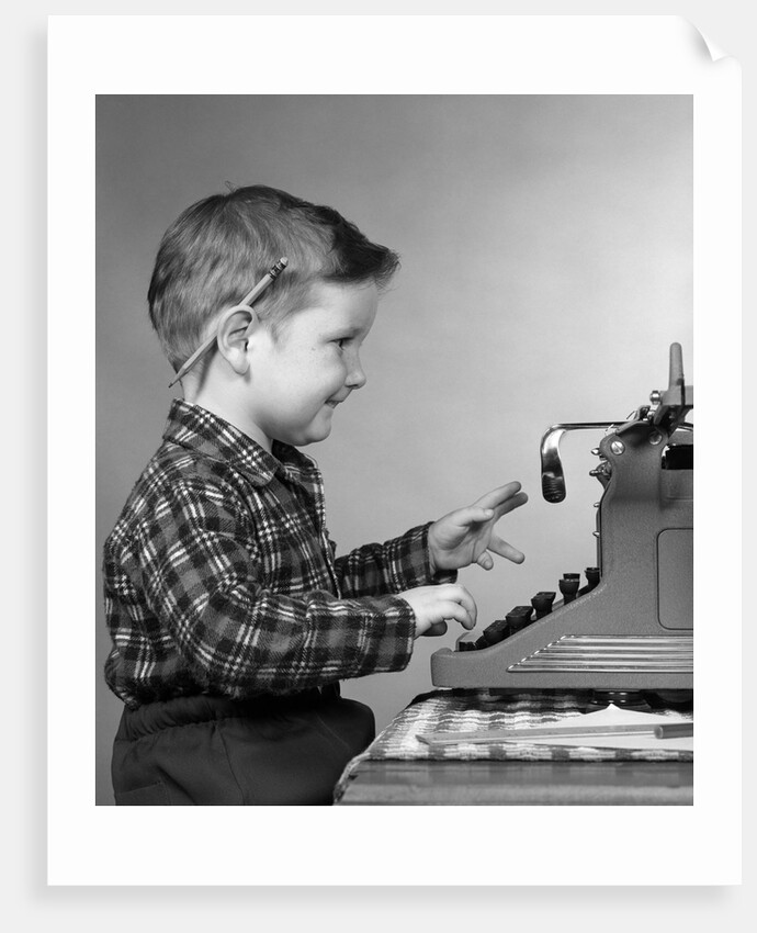 1950s smiling young boy typing on typewriter by Anonymous