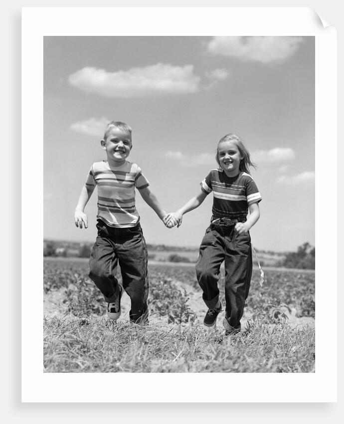 1950s boy girl running grassy farm field holding hands by Anonymous