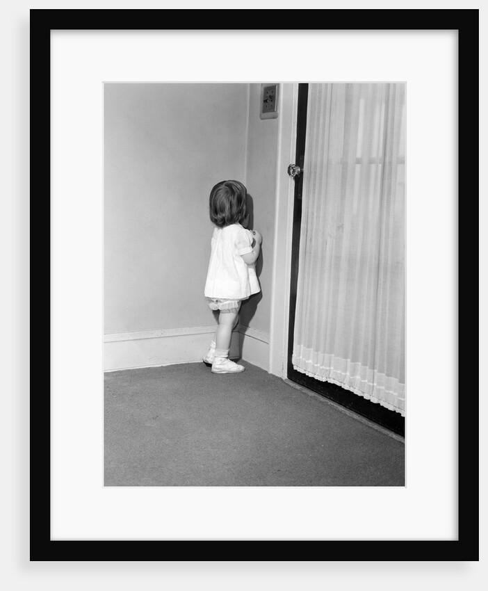 1950s 1960s little girl in white dress being punished standing in a corner by Anonymous