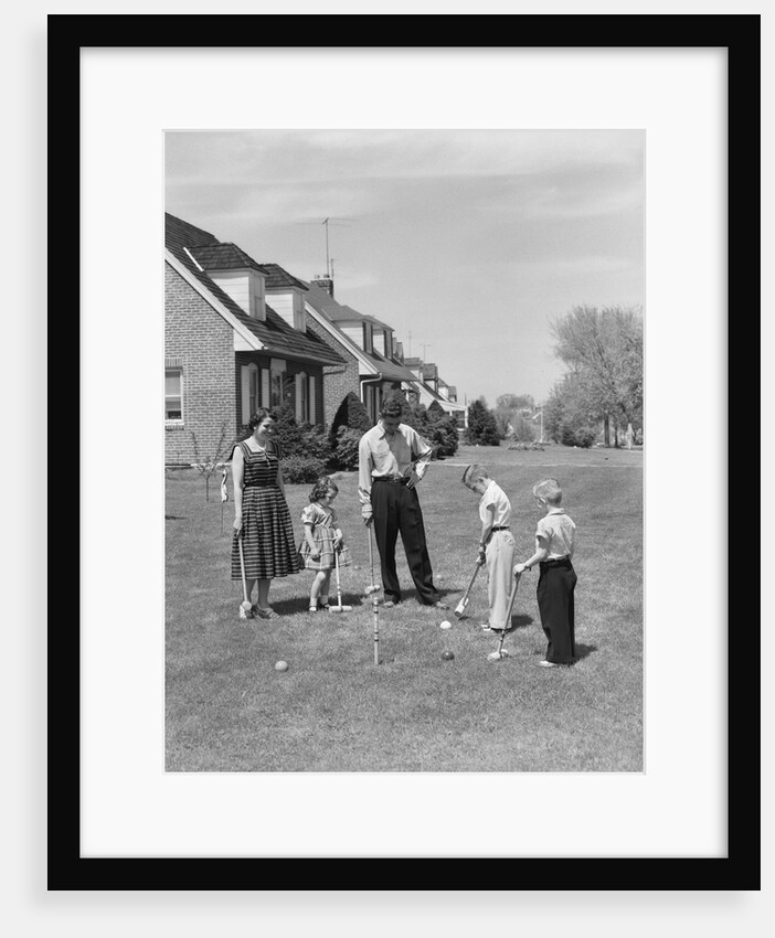1950s family mother father 3 children playing croquet front lawn suburban home by Anonymous