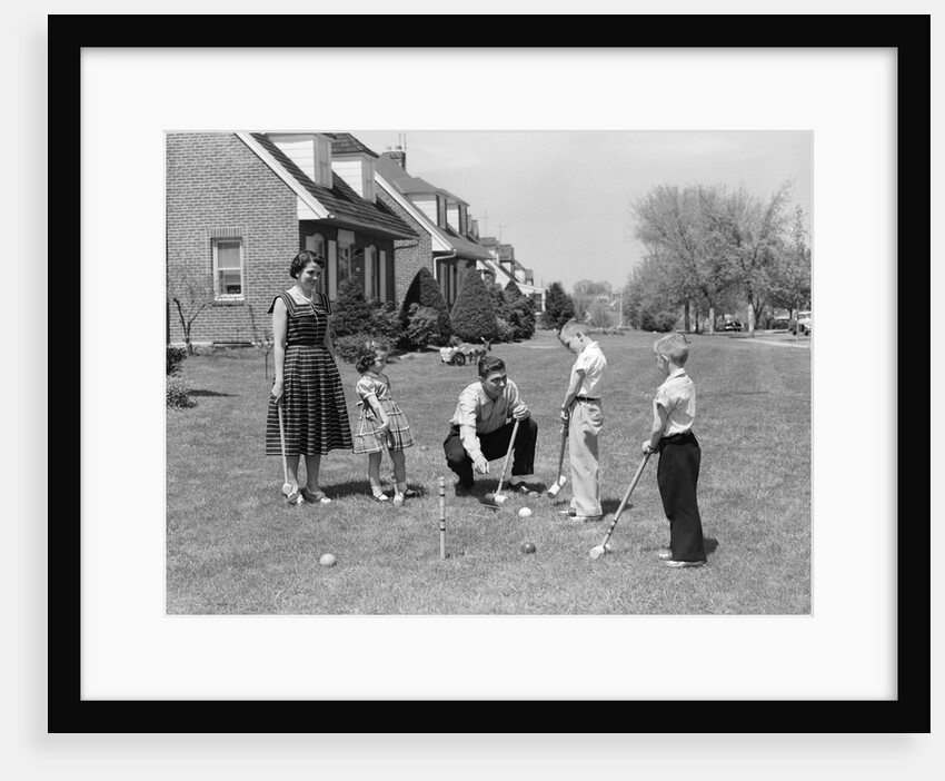 1950s family mother father 3 children playing croquet front lawn suburban home by Anonymous