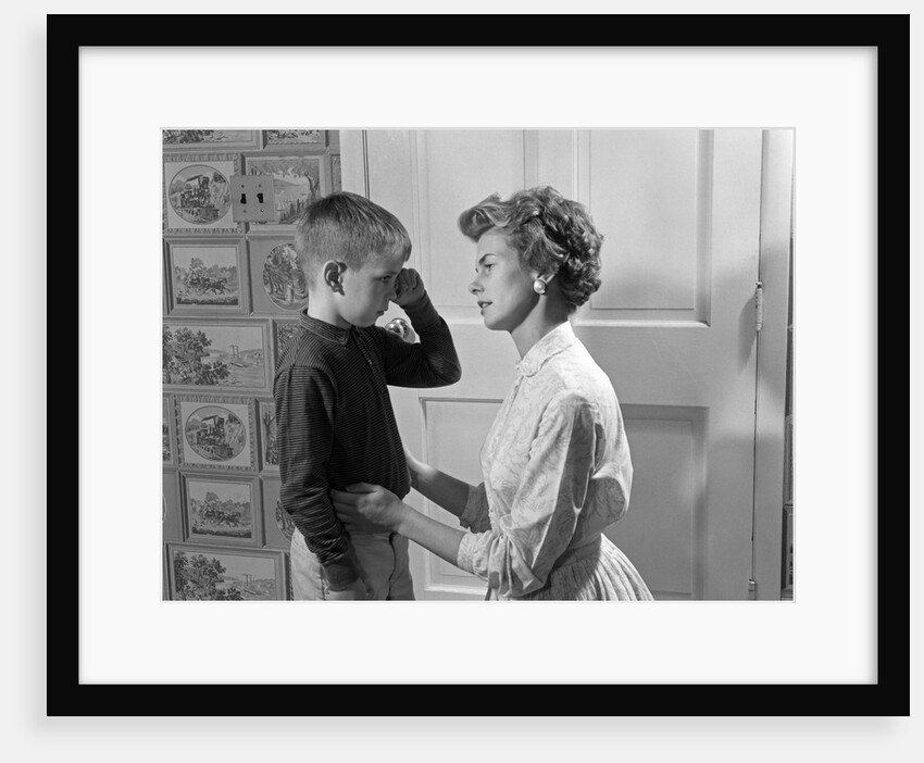 1960s sad crying boy rubbing his eyes is comforted or disciplined by his caring mother by Anonymous