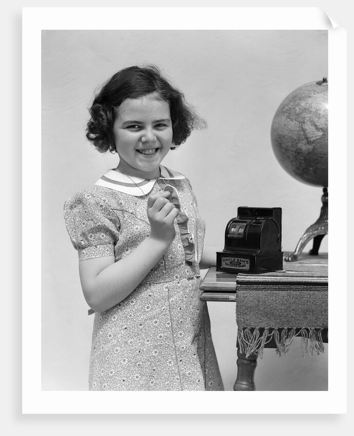 1930s child smiling girl putting money coin into toy cash register bank by Anonymous