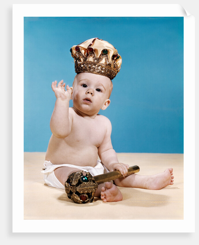 1960s baby wearing cloth diaper and crown holding a scepter waving with one arm raised looking at camera by Anonymous