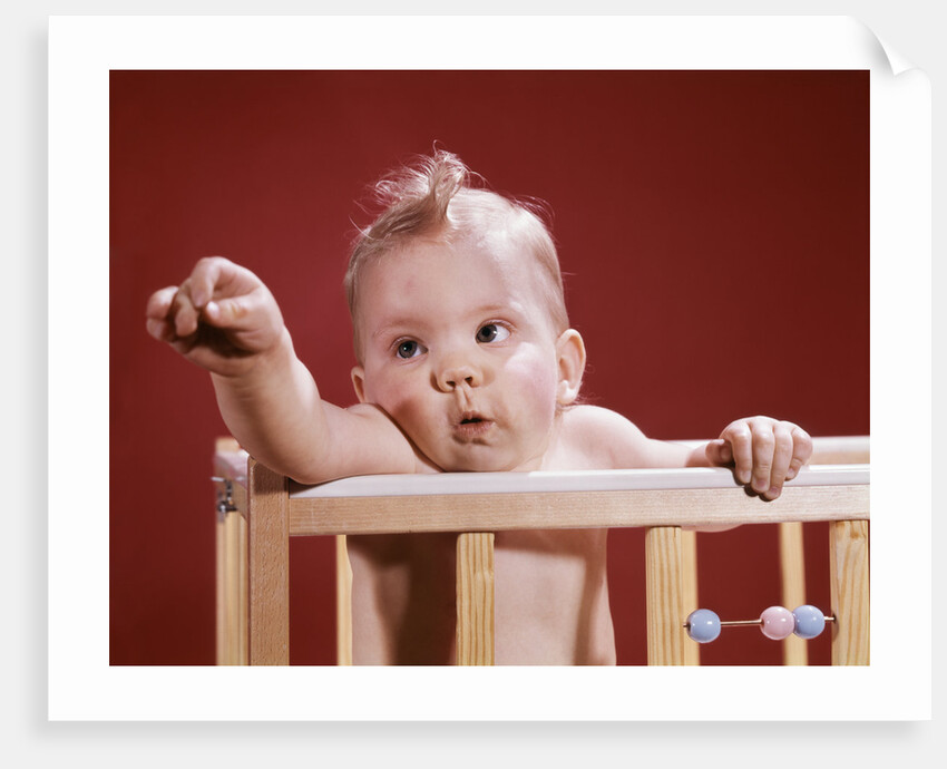 1960s baby reaching out from crib by Anonymous