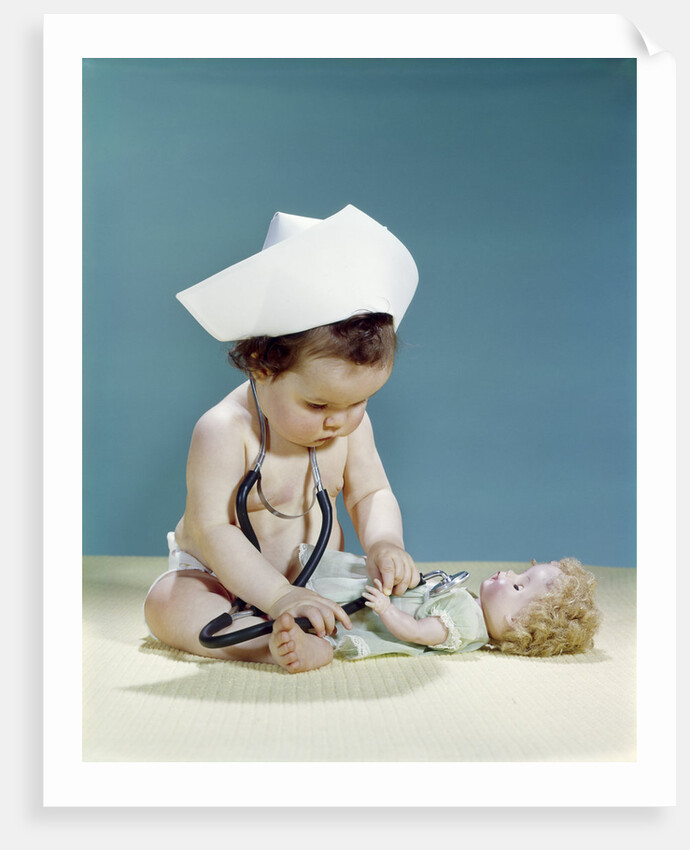 1960s baby wearing nurse nurse's cap stethoscope listening to doll heartbeat chest by Anonymous