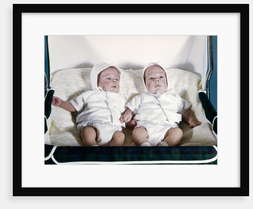 1950s 1960s twin boys dressed in white lying in stroller side by side by Anonymous