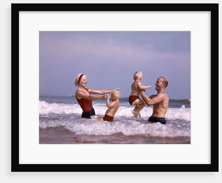 1970s family father mother two sons laughing hand holding jumping in ocean surf at beach having fun together by Anonymous