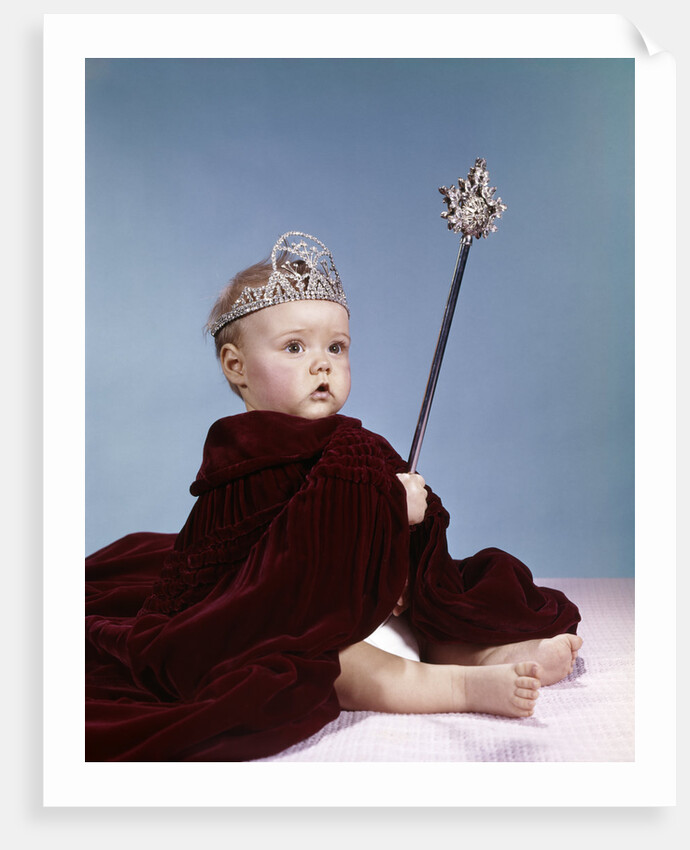 1960s baby girl wearing rhinestone tiara and red velvet cloak holding scepter by Anonymous