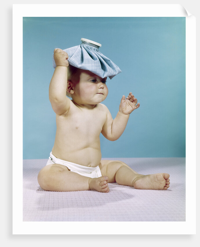 1960s baby sitting with ice pack on top of head by Anonymous