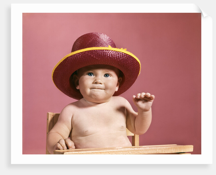 1960s baby making face wearing red straw hat by Anonymous