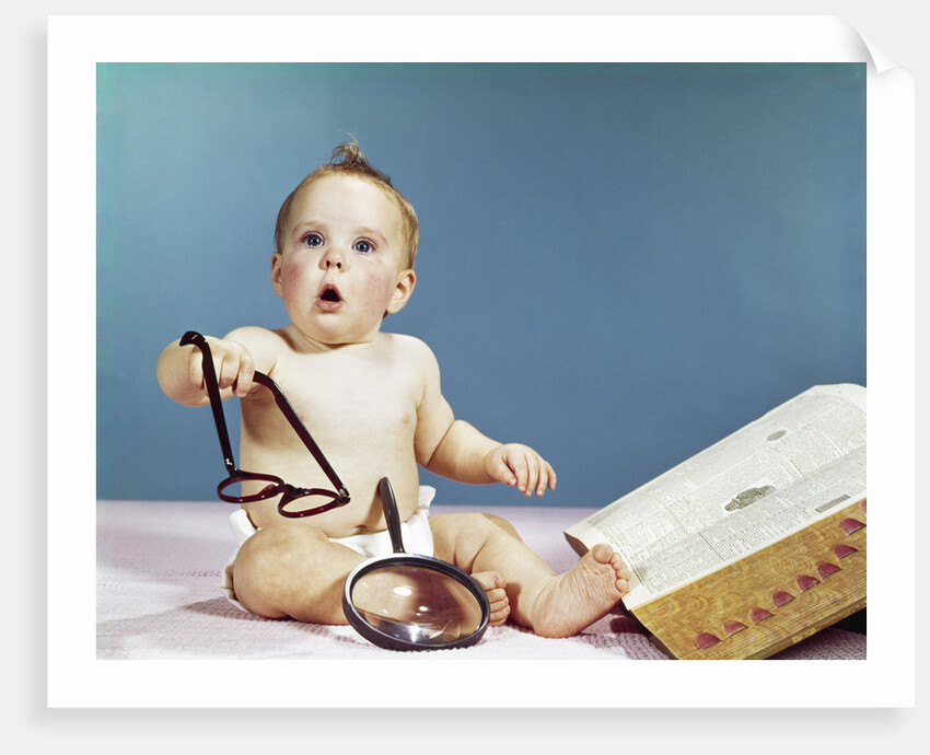 1960s baby holding eyeglasses with open dictionary and magnifying glass research by Anonymous