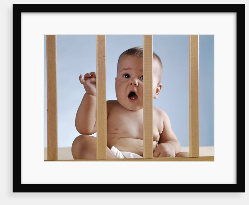 1960s baby in crib or playpen looking through bars alarmed expression by Anonymous