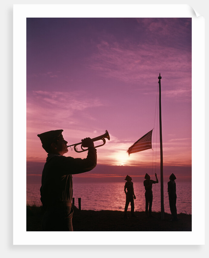 1960s boy scout blowing bugle as others raise american flag at camp sunset ceremony by Anonymous