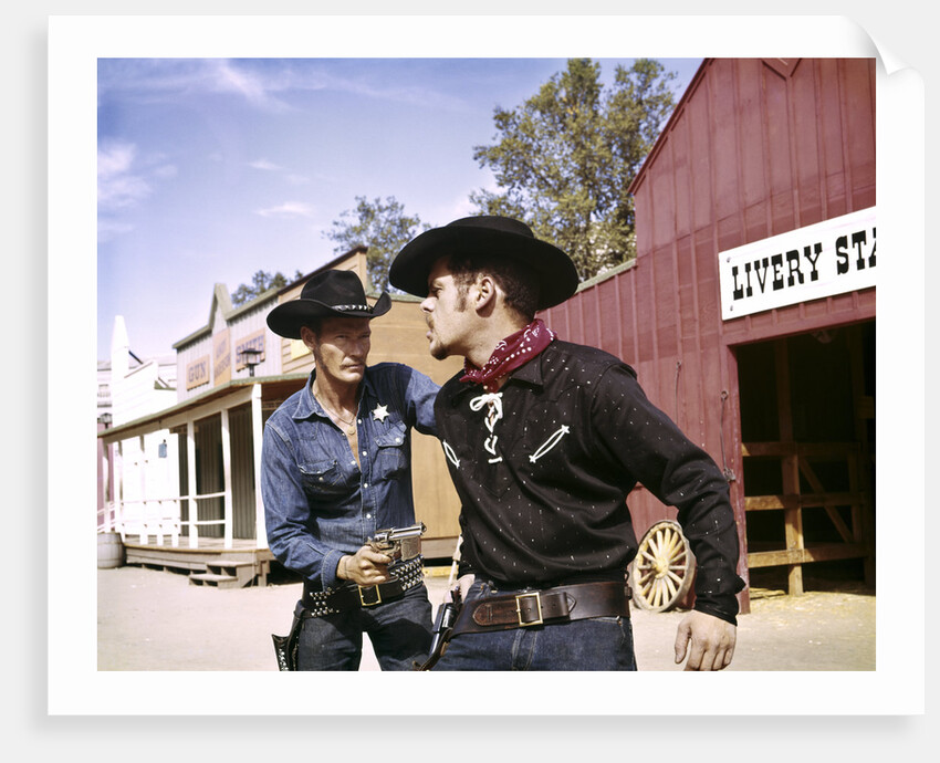 1960s cowboy sheriff with badge draws gun arrests gunfighter in front of livery stable by Anonymous