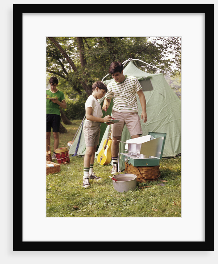 1960s three boys at campsite cooking camp stove eating food tent teens by Anonymous