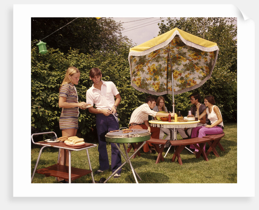 1970s group teenagers boys girls backyard grilling table umbrella by Anonymous
