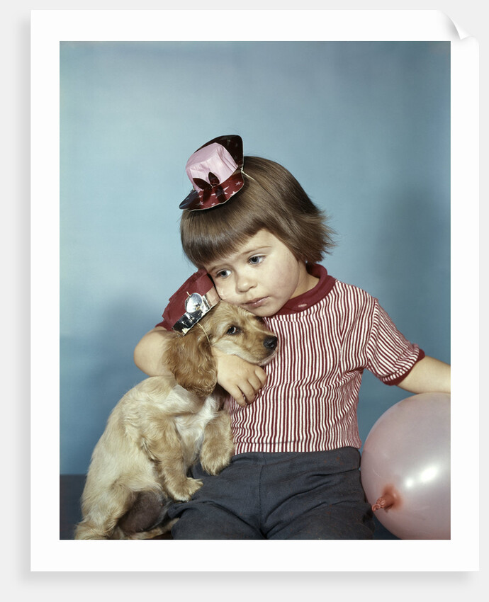 1950s 1960s little girl wearing party hat frowning hugging a cocker spaniel puppy by Anonymous